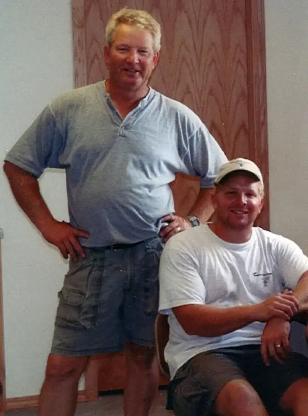 Two men standing side by side in a well-lit room, engaged in conversation.